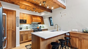 Una cucina moderna con mobili in legno, un'isola centrale con sgabelli, un forno a microonde e un fornello.