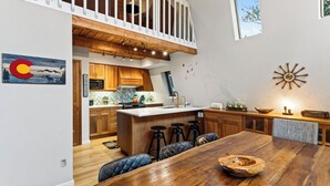 Una cucina moderna con mobili in legno, un'isola centrale, sgabelli da bar e un tavolo da pranzo.