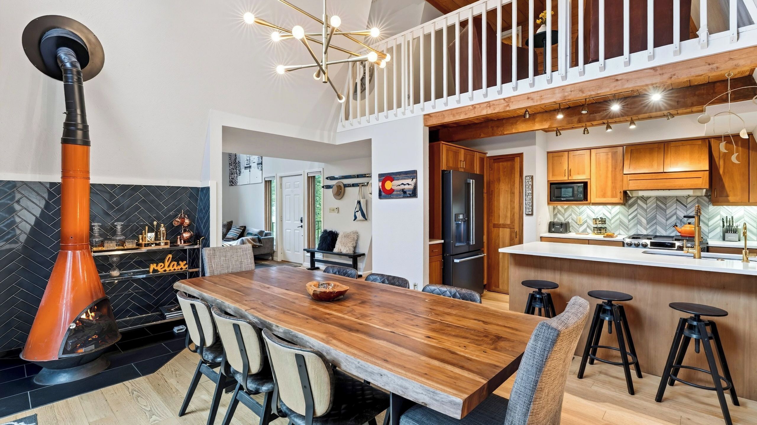 A modern kitchen with a central island, bar stools, and a fireplace.