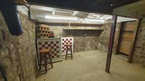 A room with stone walls, a checkered wall tile, a bar area with stools, and a wooden door.