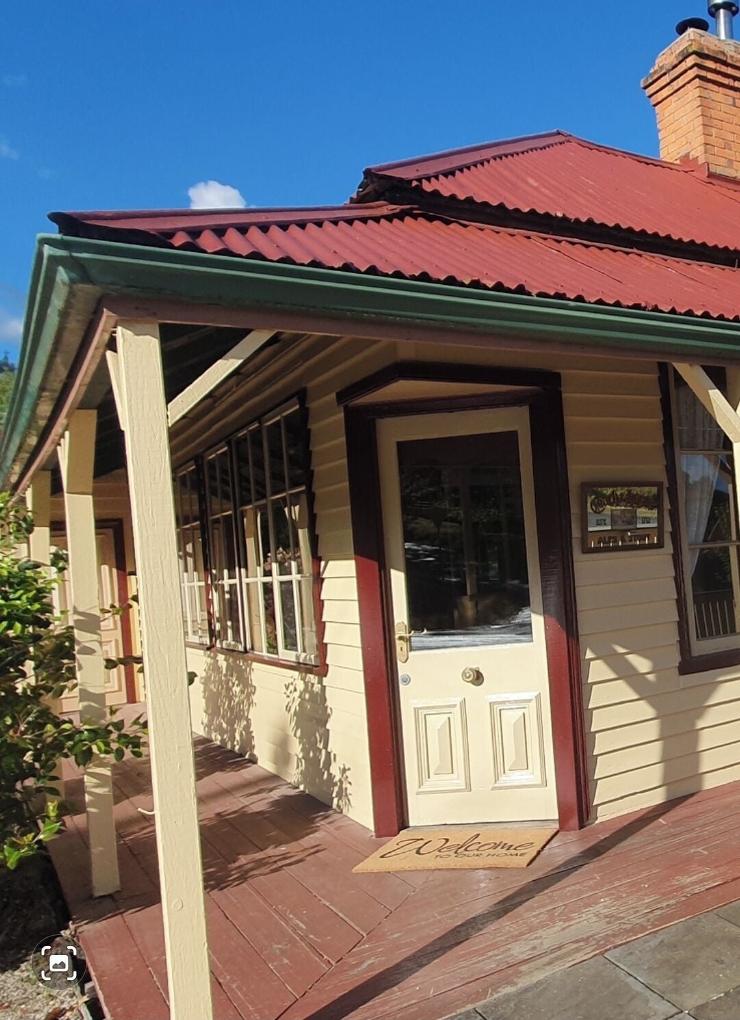 A building with a red roof, a porch with a green railing, and a door with a welcome mat.