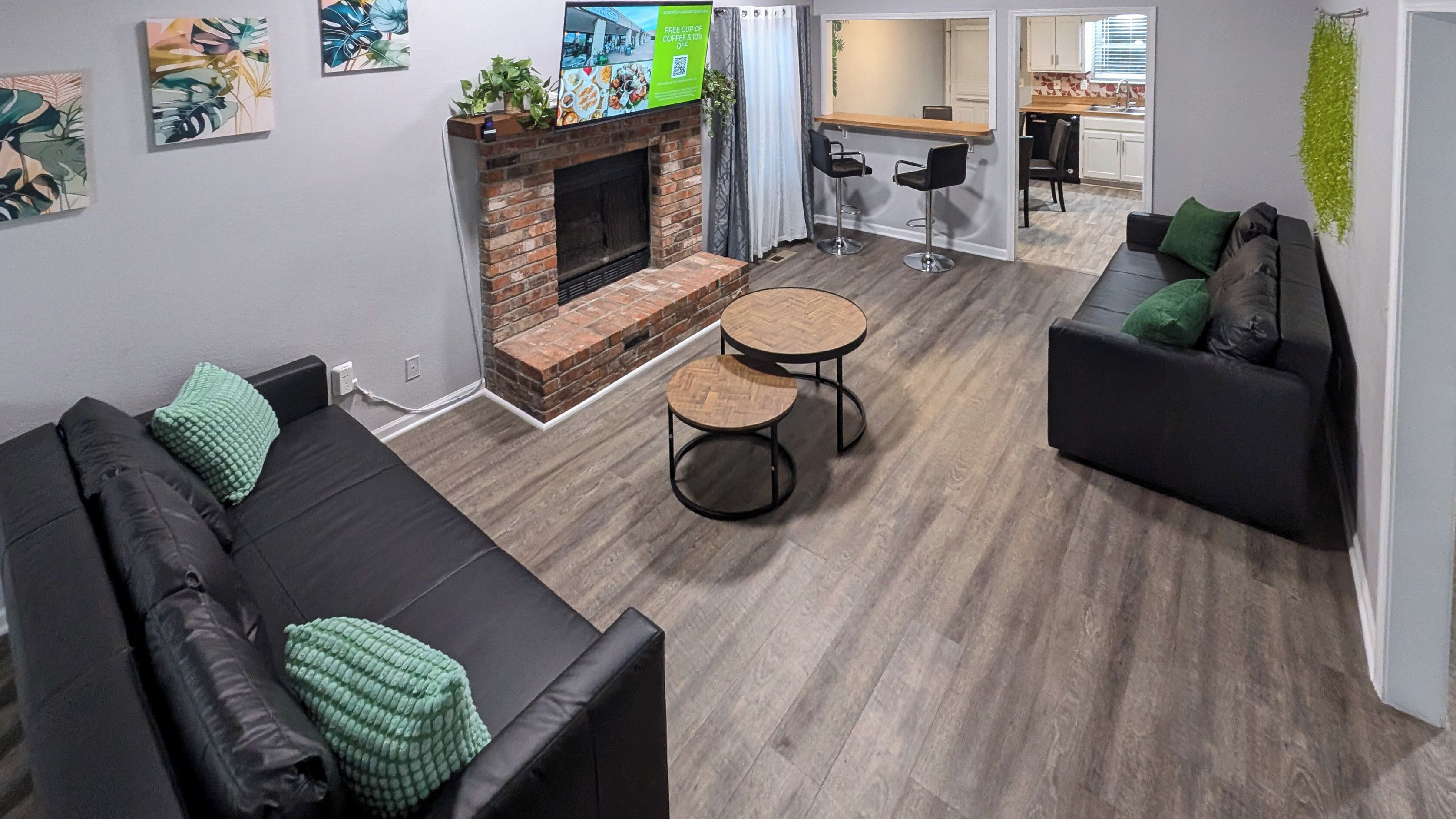 Un salon moderne avec une cheminée, un canapé, un coin repas et une cuisine en arrière-plan.