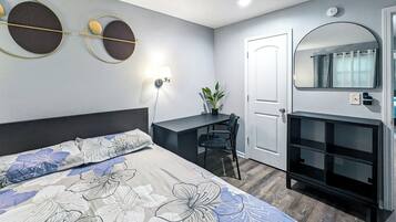 Hotellihuone, jossa on sänky, työpöytä, tuoli ja peili.