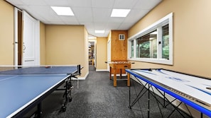 Un couloir avec des tables de ping-pong, une table en bois et une fenêtre donnant sur des arbres.