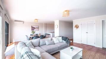 A modern living room with a sectional sofa, a coffee table, and a dining area in the background.