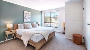 A bedroom with a bed, a nightstand, a window, and a wall-mounted artwork. - The Rooftop - Bicheno Accommodation (Bicheno)