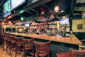 A bar with multiple screens, a long counter, and several wooden chairs. - Maui Paradise Awaits! Direct Ocean Views, Swimmable Beach & On-Site Dining (Lahaina)