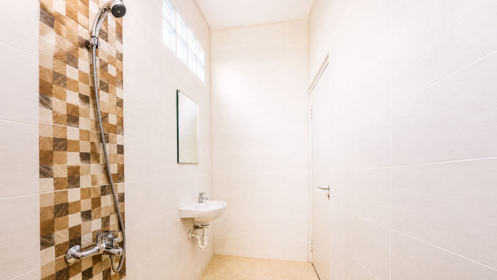 Une salle de bain avec une douche, un lavabo et des murs carrelés.