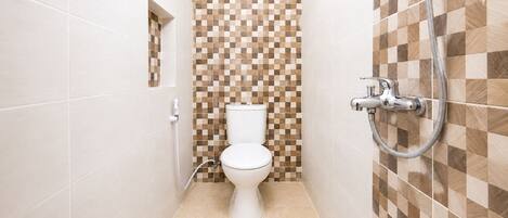 Un baño con inodoro, ducha y pared de baldosas a cuadros.