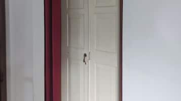 Una puerta blanca con un arco de madera encima, una cortina roja y un suelo de baldosas.