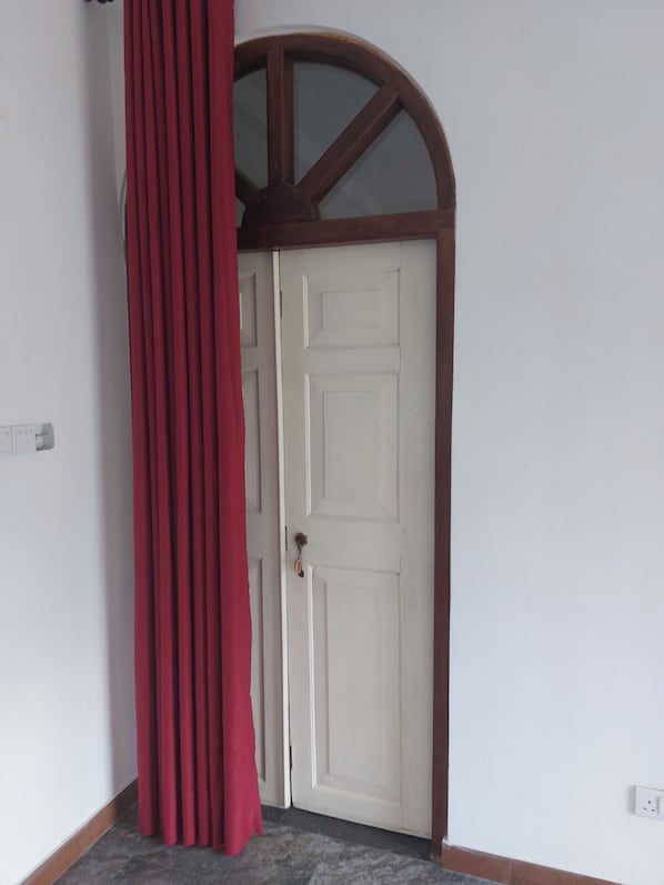 A white door with a wooden frame and a red curtain partially drawn to the side.