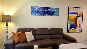 A living room with a dark brown sofa, two cushions, a glass candle holder, and two abstract paintings on the wall. - Private terrace 2-bedroom apartment in Playa Hermosa, Family &Pet friendly (Playa Hermosa)