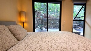 A bedroom with a bed, a lamp, and a view of a garden through a sliding door. - Private terrace 2-bedroom apartment in Playa Hermosa, Family &Pet friendly (Playa Hermosa)