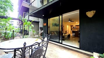 A patio with a round table and chairs, a sliding glass door leading to an interior space with a ceiling fan, and a decorative wall plaque.