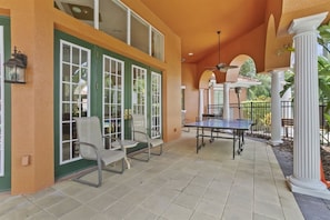 An outdoor patio area with a ping pong table, chairs, and a ceiling fan. - Gameroom 2kingbeds Neardisney (Davenport)