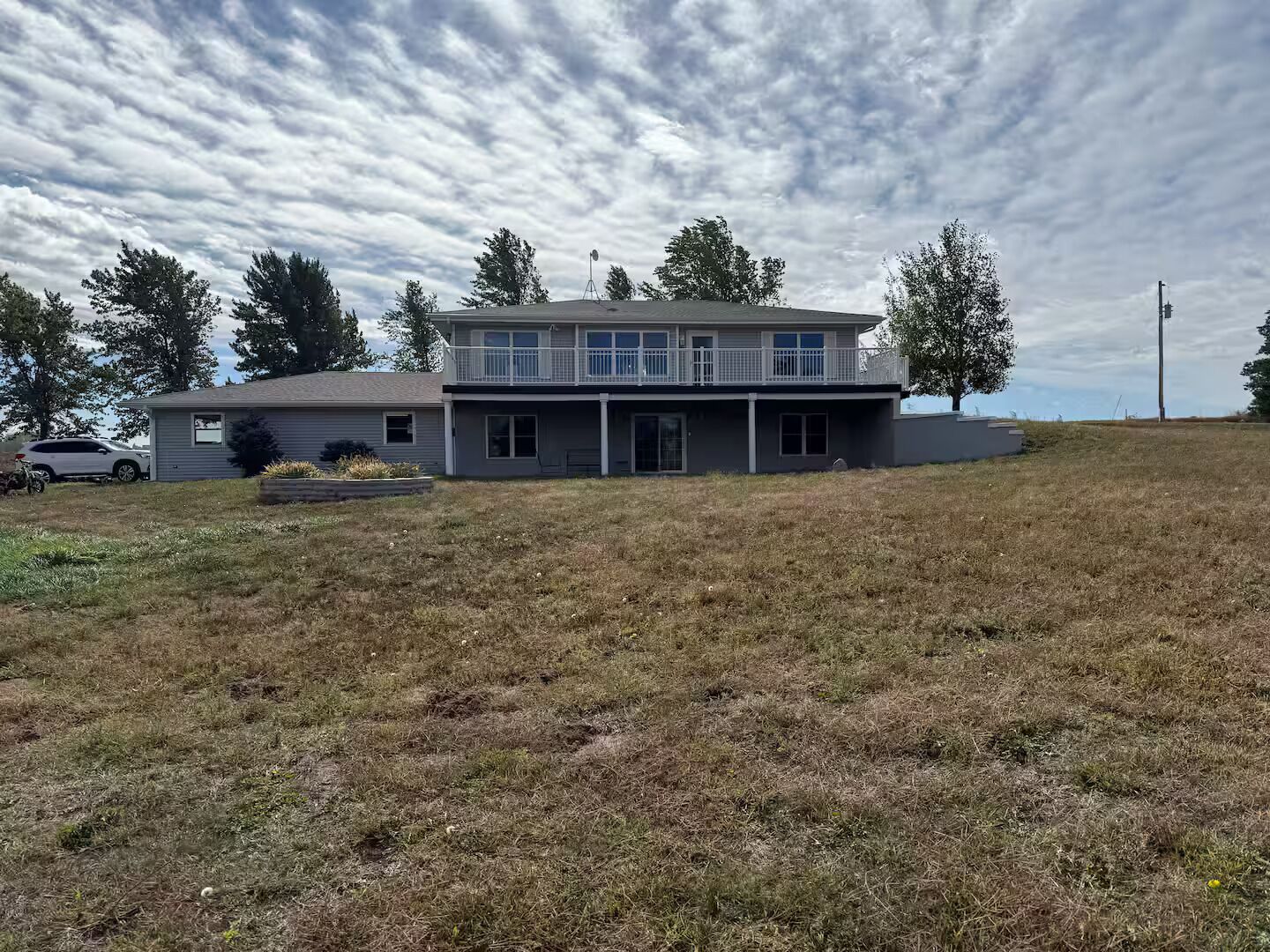 A two-story house with a balcony, a garage, and a grassy yard.