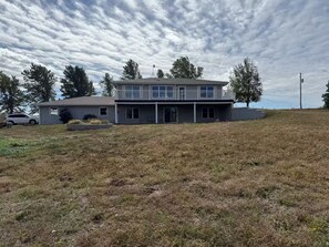 A two-story house with a balcony, a garage, and a grassy yard.