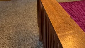 Una stanza con testiera in legno, pavimento coperto di moquette e bagno in evidenza sullo sfondo.