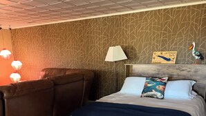 Una camera d'albergo con un letto, un comodino, una lampada e una parete decorata con un motivo.