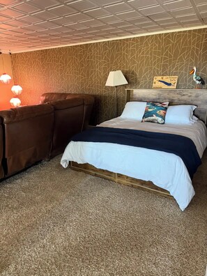 A hotel room with a bed, a nightstand, a lamp, and a wall with a patterned design. - Spacious 4-bedroom house at peaceful Lake McConaughy. (Brule)