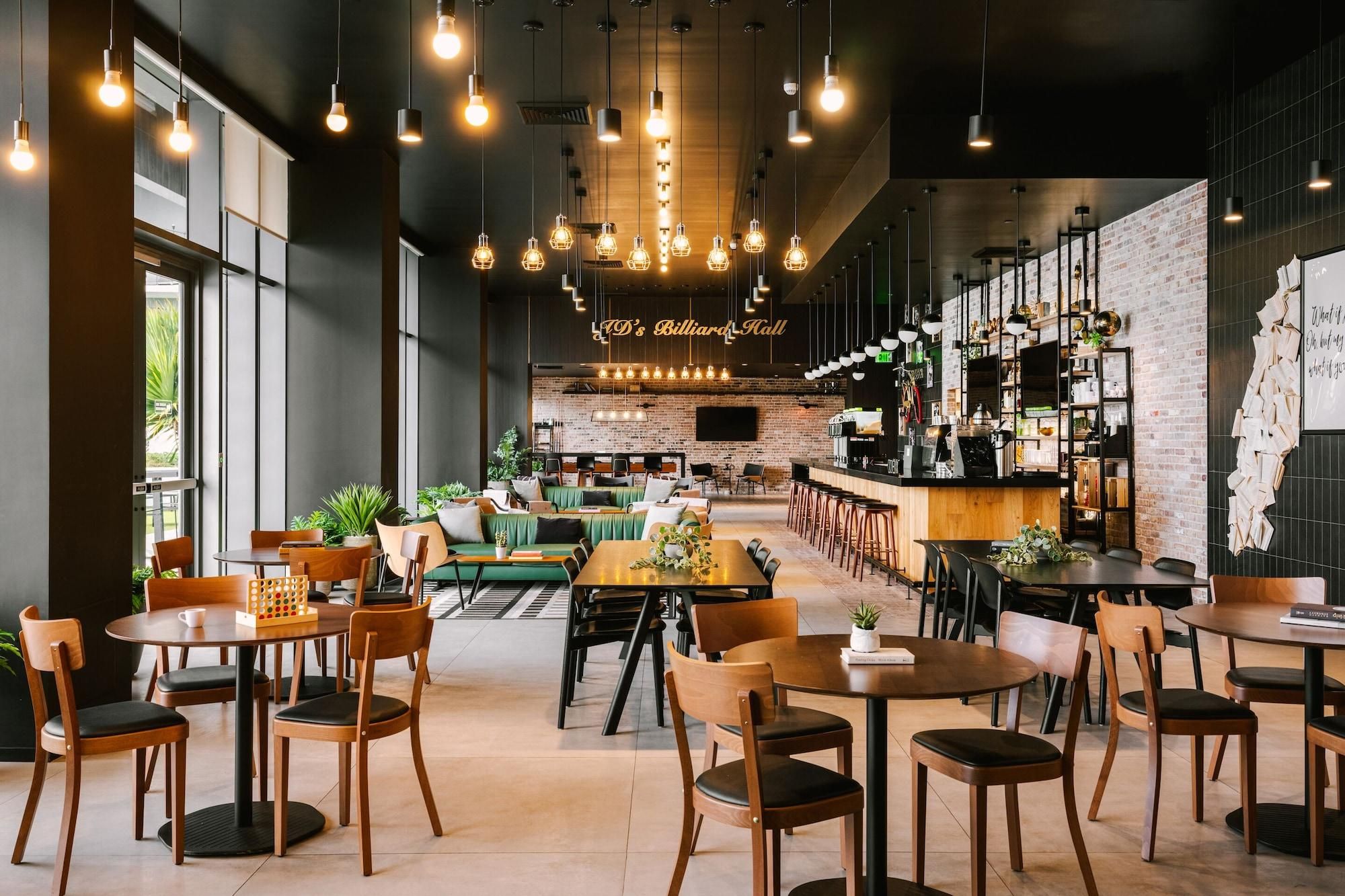A spacious indoor area with multiple seating arrangements, including tables and chairs, and a bar area with shelves and a counter.