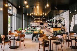 Un amplio espacio interior con diversas opciones de asientos, incluyendo mesas y sillas, y una zona de bar con estantes y mostrador.