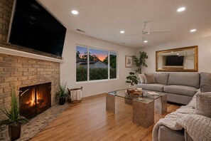 Un salon moderne avec une cheminée, une grande fenêtre, un canapé et un téléviseur à écran plat.