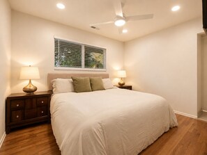 A bedroom with a bed, two bedside tables, a ceiling fan, and a window with blinds. - Casa La Vuelta - 4 King Suites Near Miramar Beach (Montecito)