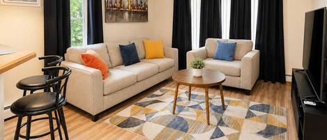 A living room with a sofa, two chairs, a coffee table, and a TV.