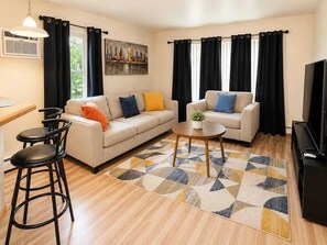 A living room with a sofa, two chairs, a coffee table, and a TV.