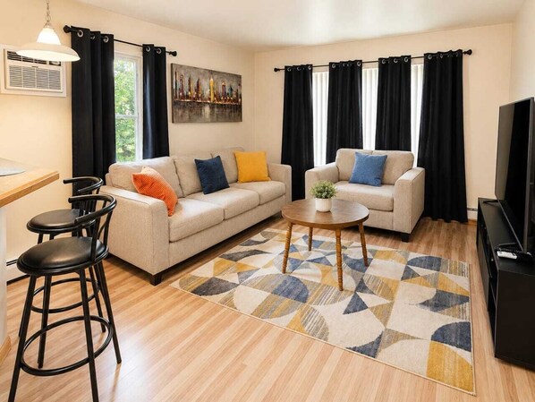 Una sala de estar con un sofá, dos sillones, una mesa de centro y un televisor.