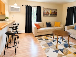 A living room with a sofa, two chairs, a coffee table, and a patterned rug.