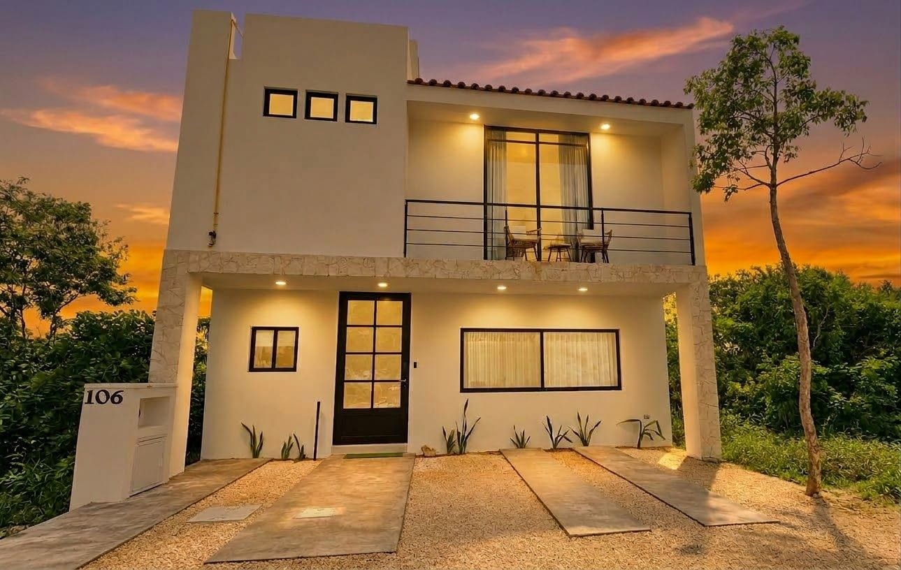 A two-story house with a balcony, a front door, and a number '106' sign.