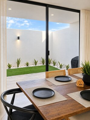Un espace repas moderne donnant sur un jardin aménagé grâce à de grandes portes coulissantes.