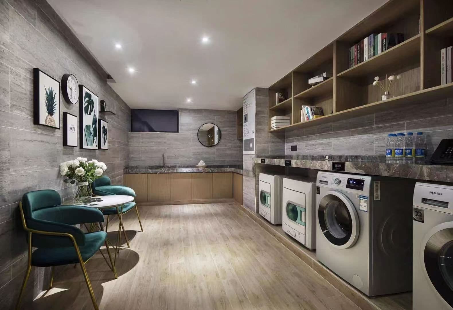 A modern kitchen with built-in appliances, a dining area with teal chairs, and a laundry station with a Siemens washing machine.