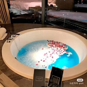 A large bathtub filled with water and rose petals, with a view of a cityscape through a window. - CNHÓL S Hotel Shenzhen Futian Port  (Shenzhen)