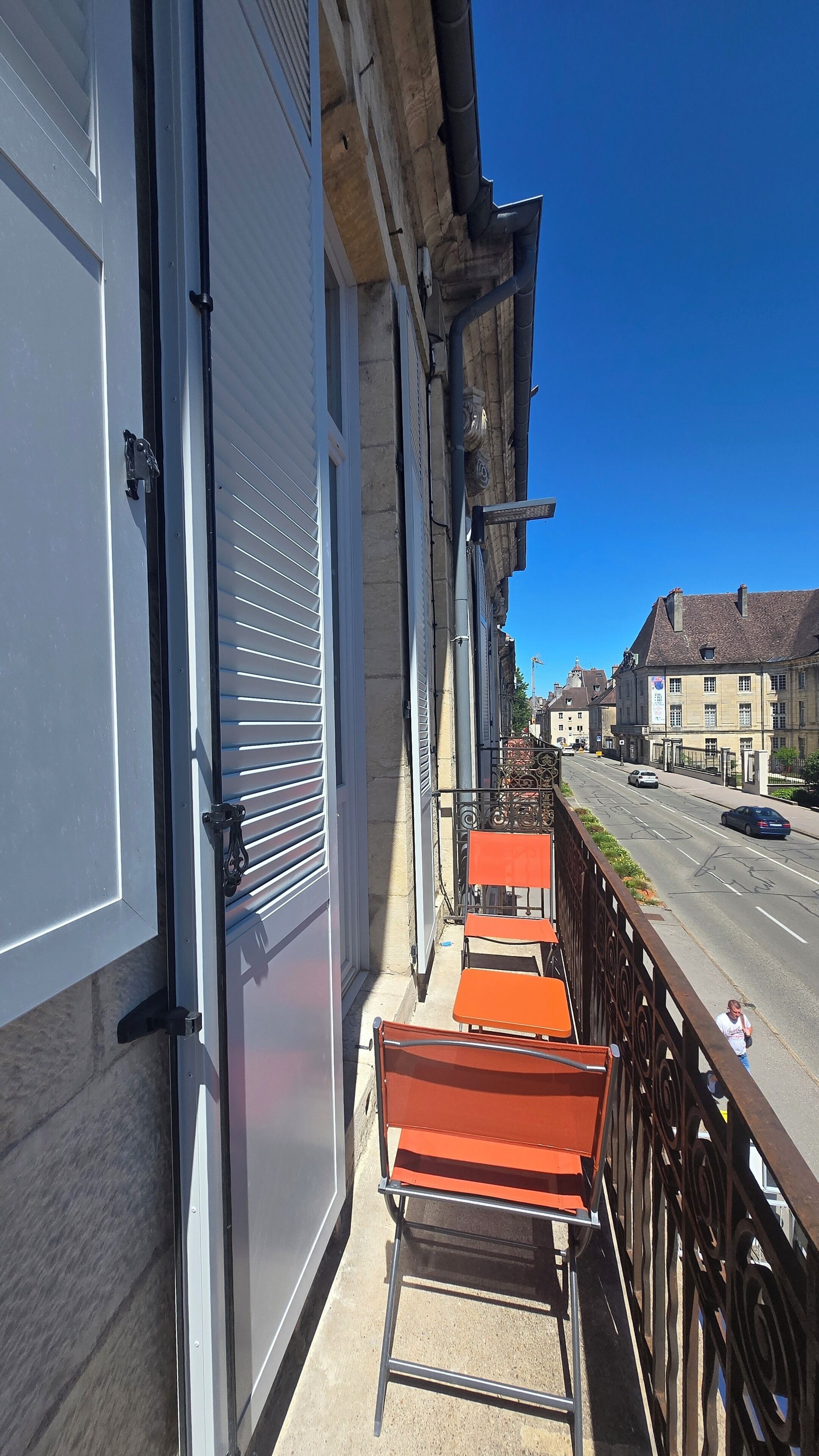 A balcony with metal railings and a row of orange chairs.