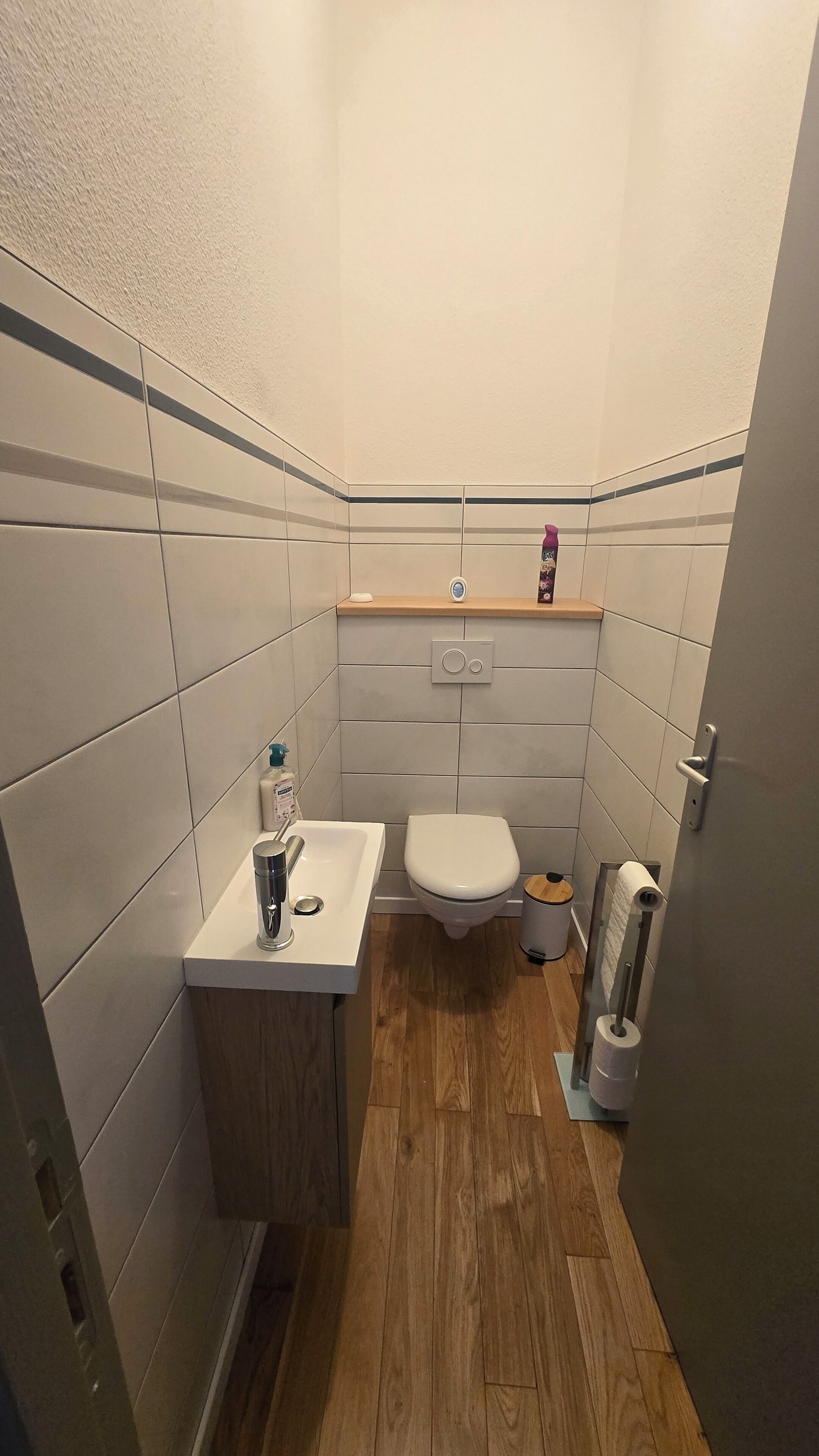 Casa de banho compacta com sanita, lavatório e um pequeno contentor de lixo.