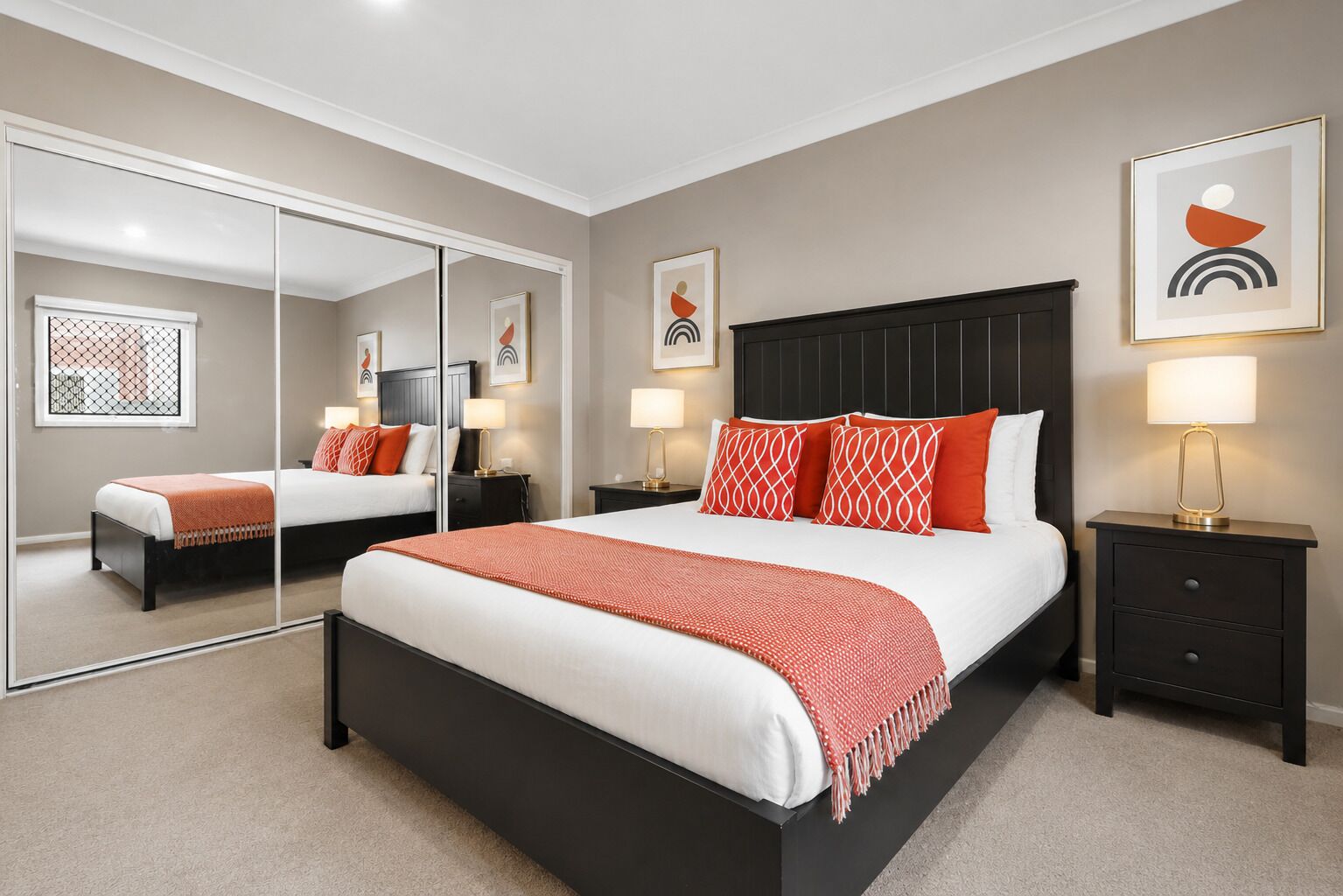 A hotel room with a large bed, two bedside tables, a mirror, and artwork on the walls.