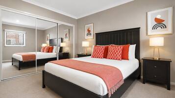 A hotel room with a large bed, two bedside tables, a mirror, and artwork on the walls.