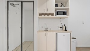 Uma cozinha compacta com micro-ondas, um pequeno frigorífico e uma pia.