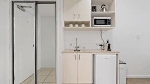 Eine kleine Küche mit einer Mikrowelle, einem kleinen Kühlschrank und einem Spülbecken.