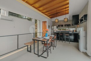 A modern kitchen with a dining area, wooden ceiling, and pendant lights.