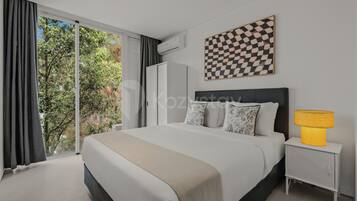 Un dormitorio moderno con una cama grande, una mesita de noche con lámpara y un cuadro de pared con diseño escocés.