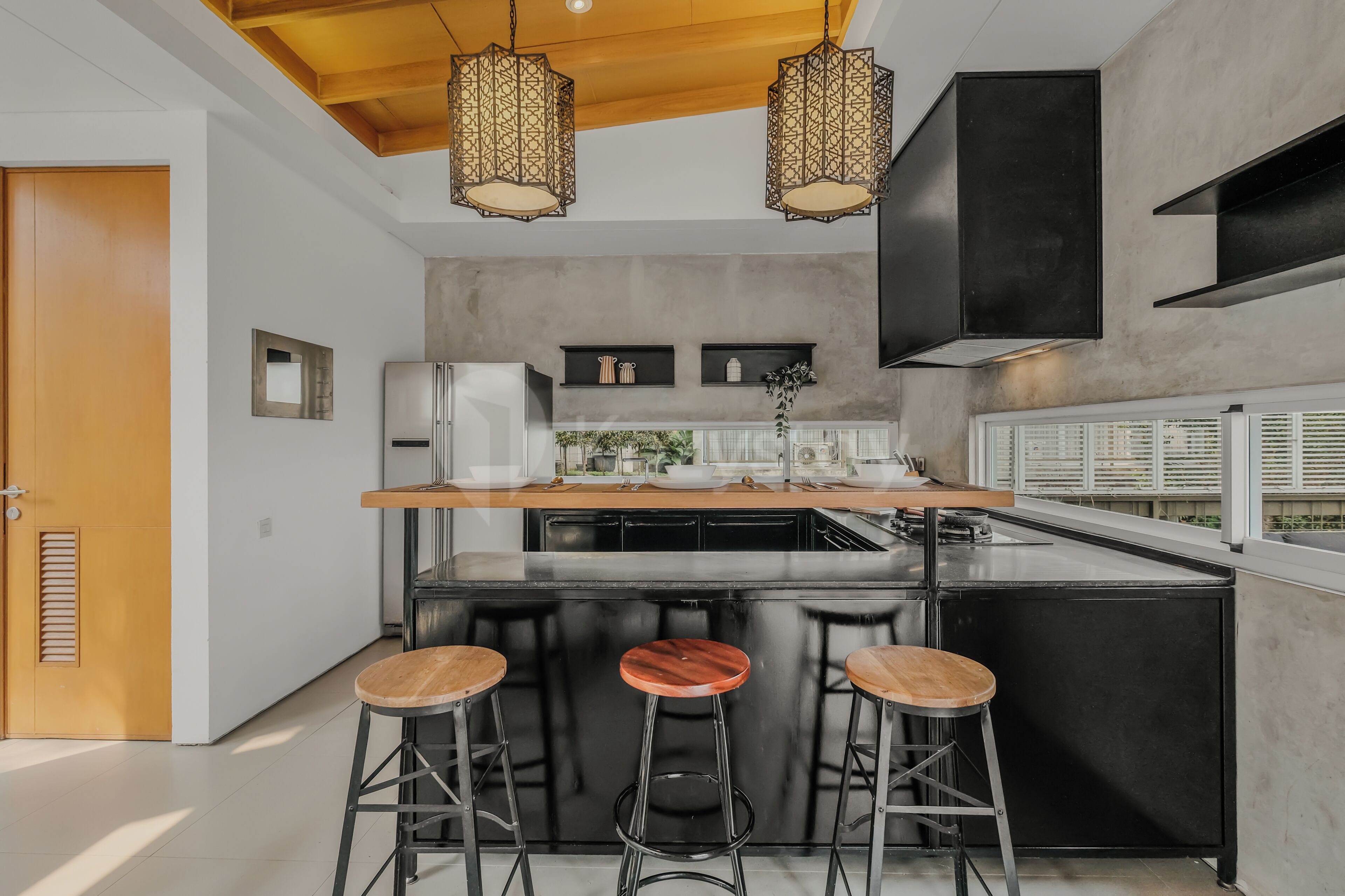 A modern kitchen with a central island, bar stools, pendant lighting, and a built-in oven.