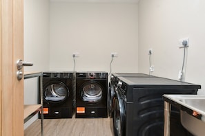 A laundry room with two front-loading washers and a stacked dryer, wooden flooring, and a door. - Contractor-friendly 6BR 6 En-suites Free Parking (Dover)