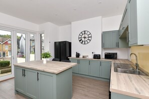 A modern kitchen with a central island, built-in appliances, and a large wall clock.