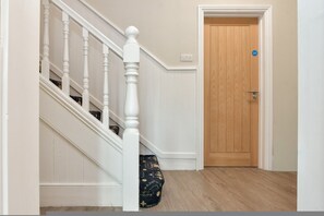 A staircase with white balusters leading to a wooden door with a blue sign.