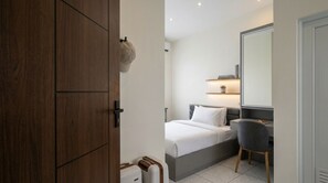 A modern bedroom with a bed, bedside table, chair, and a large mirror. - Arunava Stay by Sinergi (Semarang)