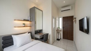 A modern hotel room with a bed, bedside table, mirror, TV, and a wardrobe. - Arunava Stay by Sinergi (Semarang)